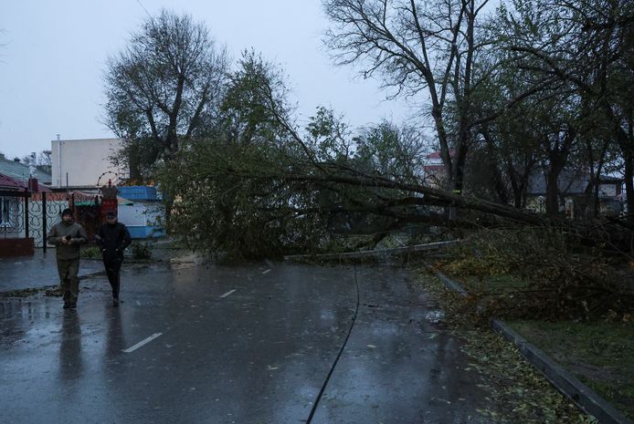 Des personnes passent devant des arbres tombés dans une rue touchée par une puissante tempête à Yevpatoriya, en Crimée, le 27 novembre 2023.