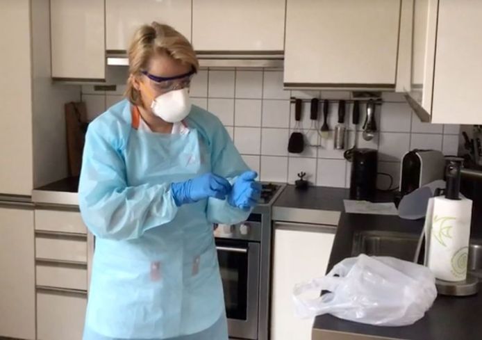 Een verpleegster van thuiszorginstantie Icare trekt haar beschermende kleding aan voordat ze binnenstapt bij een klant uit de risicogroep.