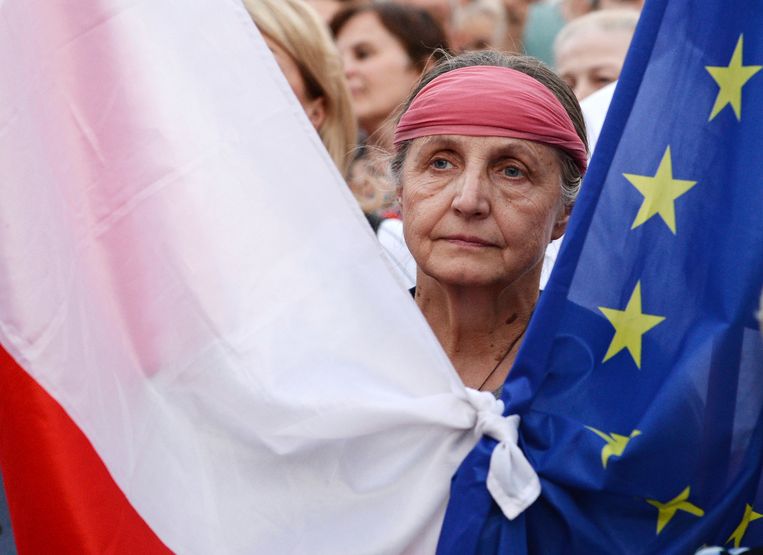 Een demonstrant houdt de vlaggen van Polen en de EU bij elkaar tijdens protesten voor het hooggerechtshof in Warschau op 4 juli. Beeld AP