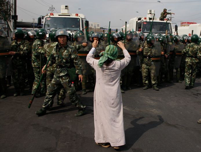 Een Oeigoerse vrouw betoogt tegen Chinese paramilitairen.