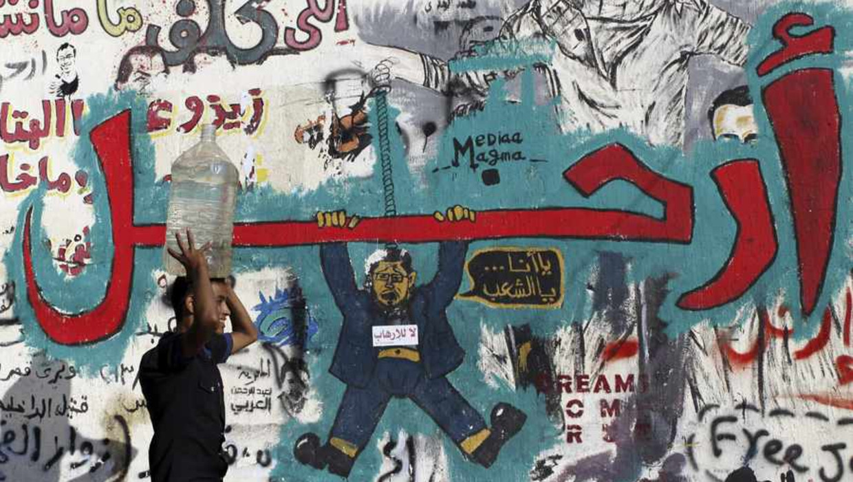 Een Egyptenaar loopt langs een wand vol anti-Morsi-graffiti. Beeld reuters