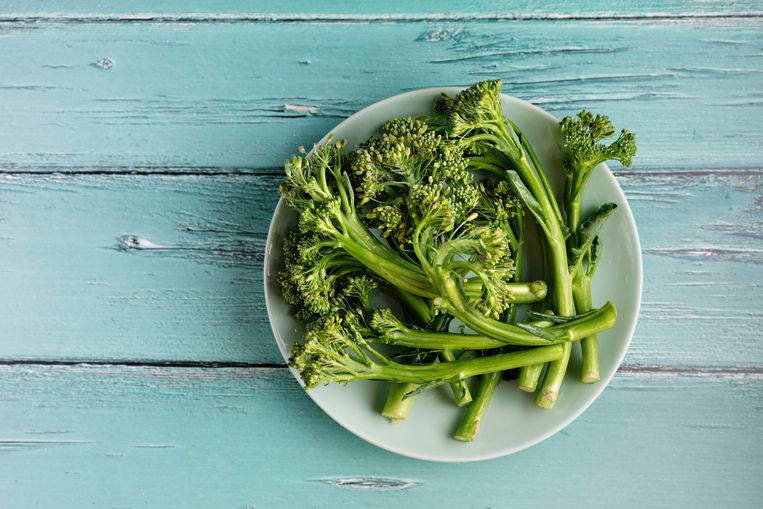 Top view of a green plate with broccolini on rustic light blue background. Helathy food concept Beeld Getty Images/iStockphoto