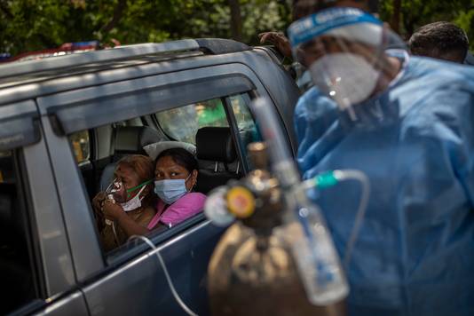 Een coronapatiënt krijgt zuurstof toegediend in New Delhi. Het zuurstoftekort is op sommige plaatsen zo groot dat mensen slechts korte zuurstofsessies in hun auto krijgen. Er staan rijen van mensen te wachten.