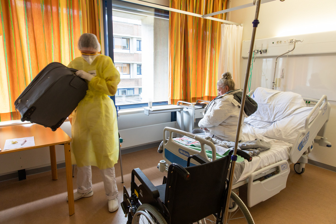 Verpleegkundige Wendy (26) haalt een rolstoel, helpt Mieke in haar jas en pakt haar koffer in.