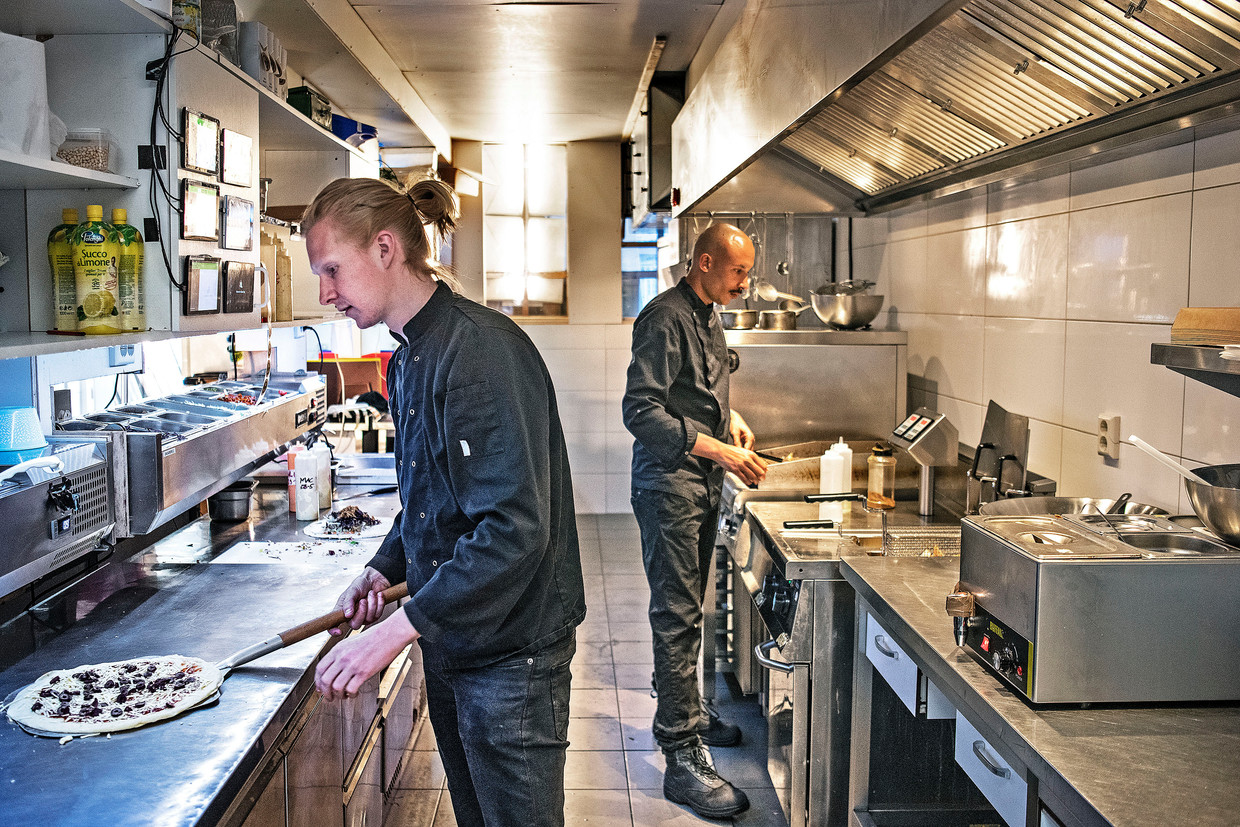 Ondernemer Rens Bekkers (links) bereidt een pizza in zijn ‘dark kitchen’ in de Amsterdamse Jordaan.  Beeld 	Foto Guus Dubbelman / de Volkskrant