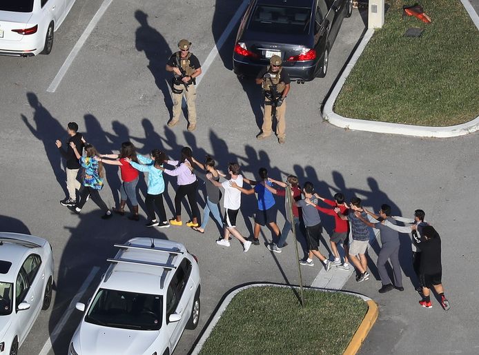Leerlingen van de Marjory Stoneman Douglas High School worden door de politie naar buiten geleid, vlak na de grote schietpartij op hun school.