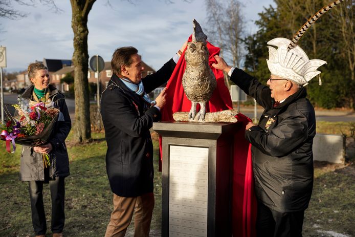 De Dorpleinse kunstenaar Nanouk Weijnen kijkt toe hoe de Cranendonckse burgemeester Roland van Kessel (l) en Jan Smits het Heiknuuterbeeld onthullen.