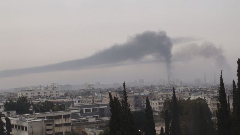 Een rookkolom verspreidt zich over Homs nadat president Assad verschillende wijken in de stad vrijdag bombardeerde. Beeld reuters