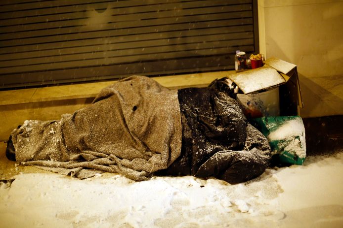 Een dakloze brengt in de bittere kou de nacht door op straat in Parijs.