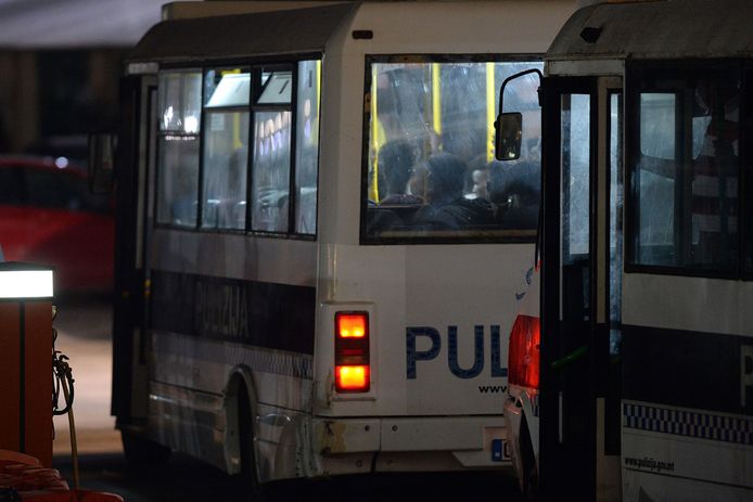 Migranten die van de Alan Kurdi afkomen, worden in politiebusjes weggebracht.