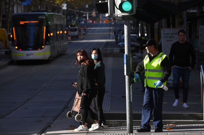 Een schoonmaker desinfecteert het knopje van een verkeerslicht in Melbourne.