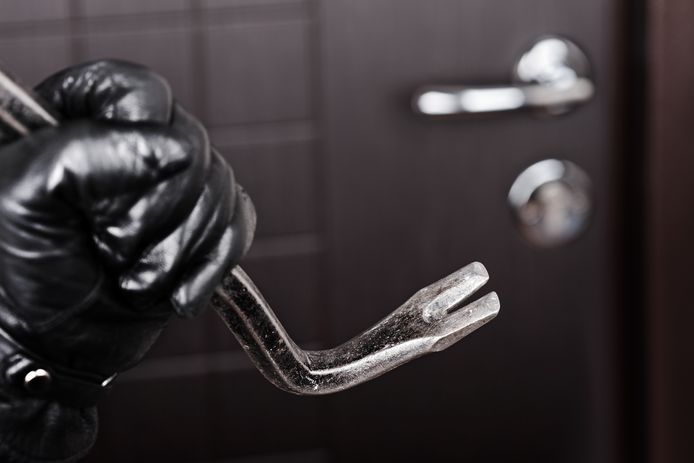 stockadr inbraak inbreker Crime scene - thief or burglar hand in gloves holding metal crowbar break opening home door lock