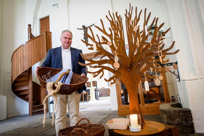 Dominee Dick Juijn met een voedselmand naast de wensboom in de toren van de Oude Blasiuskerk in Delden.