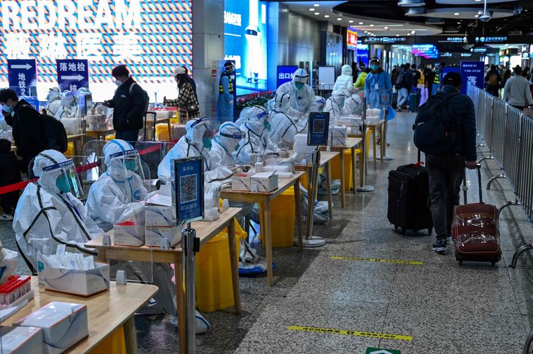 Zorgpersoneel zit klaar om reizigers te testen op corona op een treinstation in Shanghai. Beeld AFP