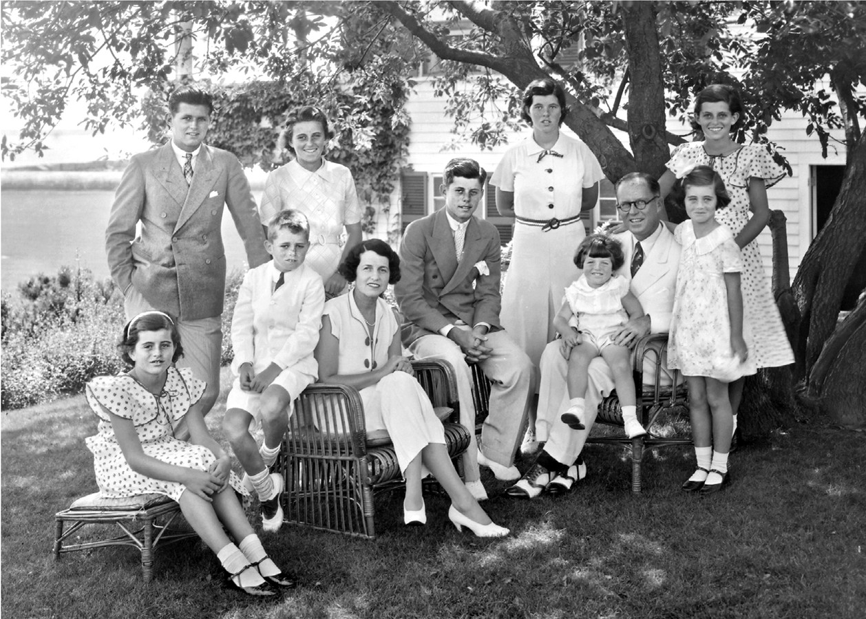 De Kennedy’s in Hyannis Port in 1934. Zittend, van links naar rechts: Pat, Bobby, Rose, Jack en Joe met Teddy op schoot. Staand: Joe Junior, Kick, Rosemary, Eunice en voor haar Jean.