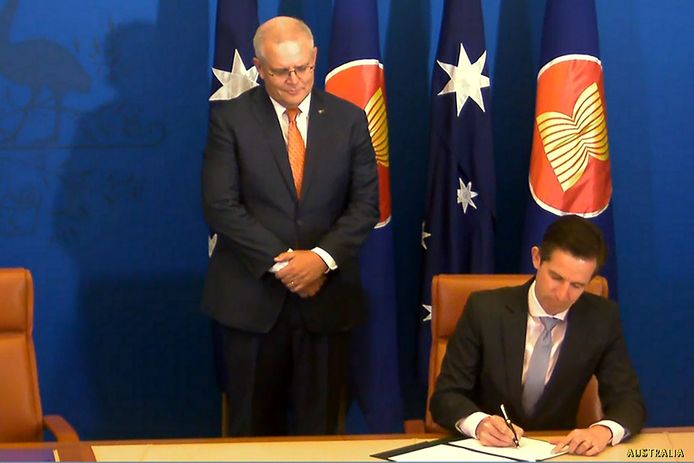 Ook Australië ontbrak niet. Premier Scott Morrison kijkt toe, terwijl de minister voor Handel, Simon Birmingham, zijn handtekening zet.