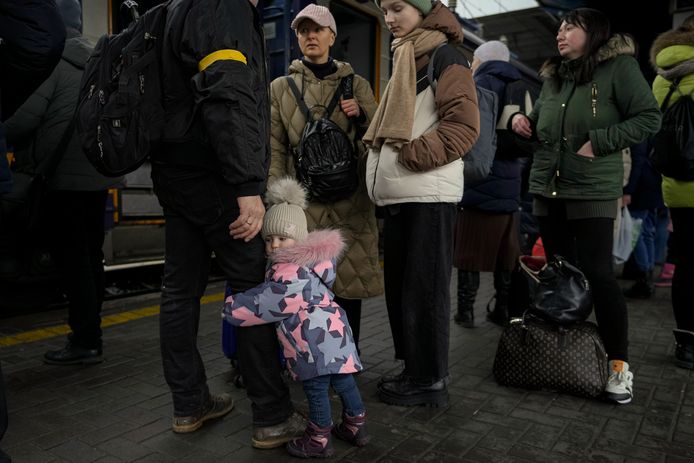 Een meisje houdt het been van haar vader vast terwijl ze in Kiev op een trein naar Lviv wacht.