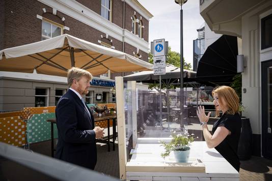 Koning Willem-Alexander praat met een horeca ondernemer bij een intake van een terras tijdens een bezoek aan de gemeente Apeldoorn. 