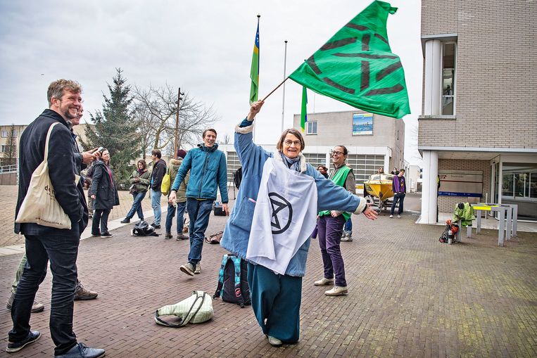 Een vrouw wappert met een vlag van Extinction Rebellion buiten het gemeentehuis in Zeewolde. Beeld Guus Dubbelman / de Volkskrant