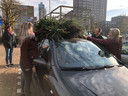 Terwijl mevrouw Mateijsen (links) toekijkt, binden haar dochter Linda en schoonzoon Patrick (rechts) met hulp van haar andere dochter Carlijn (links) twee kerstbomen boven op de auto vast.