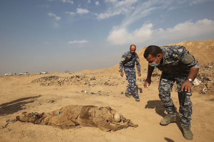Leden van het Iraakse leger helpen de lichamen op te graven.