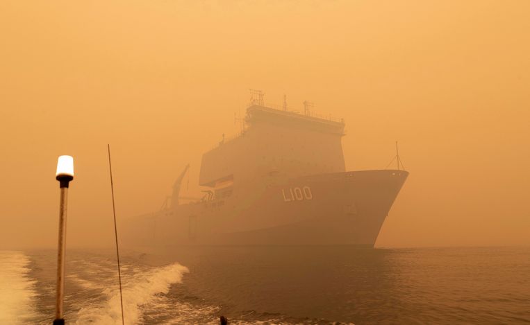 De HMAS Choules voor de kust van Mallacoota, in een dikke rookwolk als gevolg van de branden.  Beeld AP/Ministerie van Defensie Australië