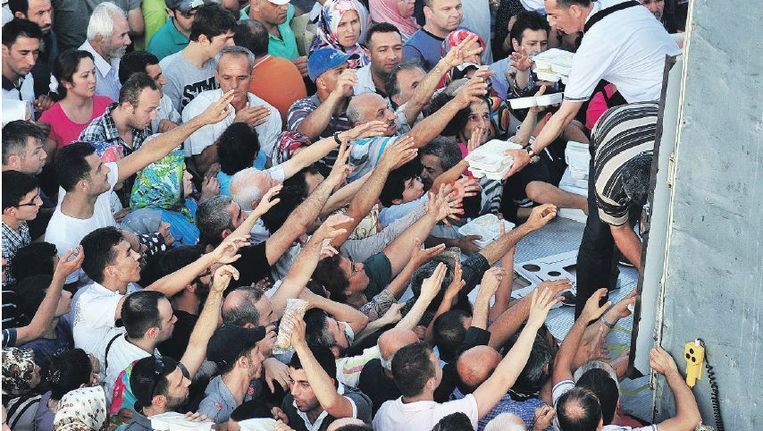 Turken krijgen in Istanbul voedsel dat aan het eind van de eerste dag van de ramadan wordt uitgedeeld. ©AFP Beeld 