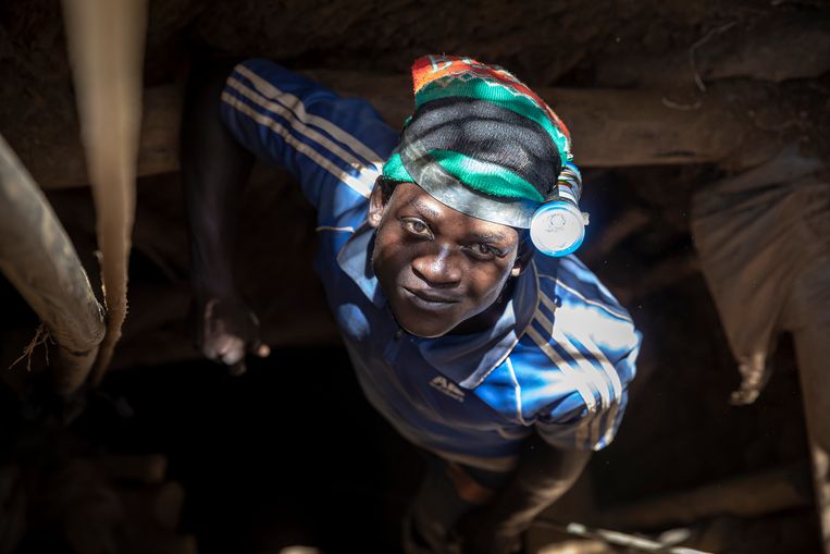 Een jongen laat zich in een van de vele schachten van de goudmijn bij Mougoumi zakken. Beeld 