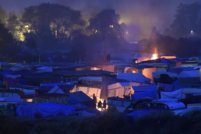 Migranten warmen zich aan een vuurtje op de tweede ochtend van de evacuatie.