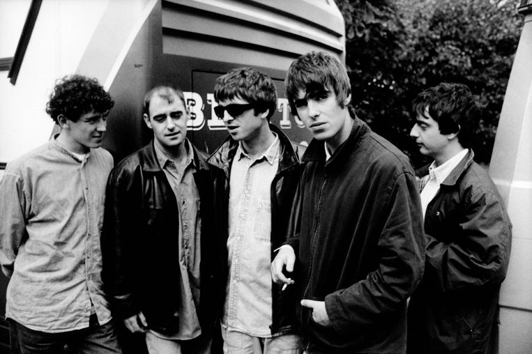 Oasis met hun originele drummer Tony McCarroll (links), die de band voor de rechter daagde omdat hij in een documentaire wordt uitgelachen om zijn beperkte capaciteiten.  Beeld Redferns