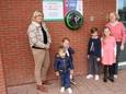 Sint-Lutgardis-directrice Veerle Notebaert en Sint-Amandus-directrice Katty Rosseel met enkele kinderen bij het nieuwe AED-toestel aan de ingang van hun scholen in de Karel van Manderstraat.