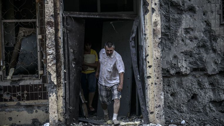 Mensen komen uit hun huis na een granaataanval in Donetsk. Beeld afp