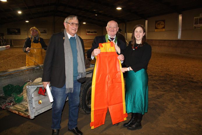 De Orde van de Paardevisser gaf de paardenvissers van Oostduinkerke een nieuwe bretellenbroek cadeau. Foto: garnaalvisser Eddy D'hulster, voorzitter Orde Marc Sirjacobs en paardenvisser Katrien Terryn. Op de achtergrond zie je Stefaan Hancke met zijn gele bretellenbroek