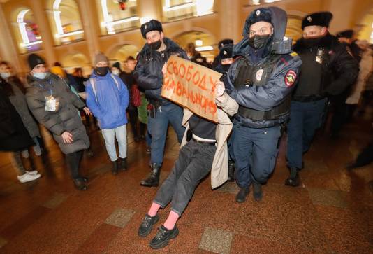 Een betoger met een bord 'Vrijheid voor Navalny' wordt afgevoerd door agenten.