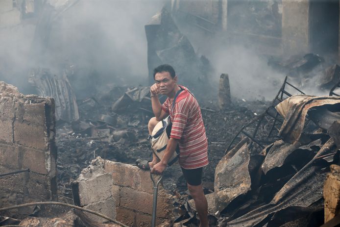 Filipijnse bewoners keren terug naar hun huis na een brand in hun wijk in Quezon City, ten oosten van Manila. Minstens 100 huizen zijn verwoest en zo’n 200 gezinnen verloren voor meer dan 15.000 euro aan bezittingen. Foto Rolex Dela Pena