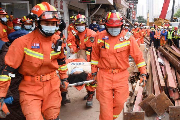 Een vrouw die meer dan vijftig uur onder het puin heeft gelegen, wordt door reddingswerkers weggedragen in Changsha, een stad in het zuidoosten van China.