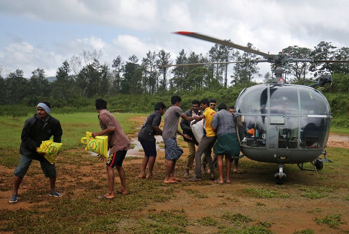 Vrijwilligers laden een helikopter uit met noodhulppakketten.