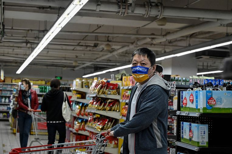 Een man in Beijing draagt een mondkapje met de tekst 'Sta achter Oekraïne', april 2022.  Beeld Jade Gao / AFP 