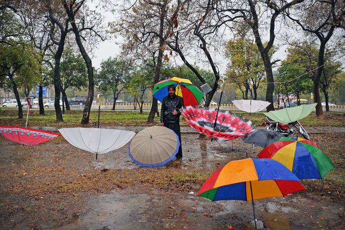 Een Pakistaanse parapluverkoper wacht op een regenachtige ochtend in Islamabad op klanten . Foto Aamir Qureshi