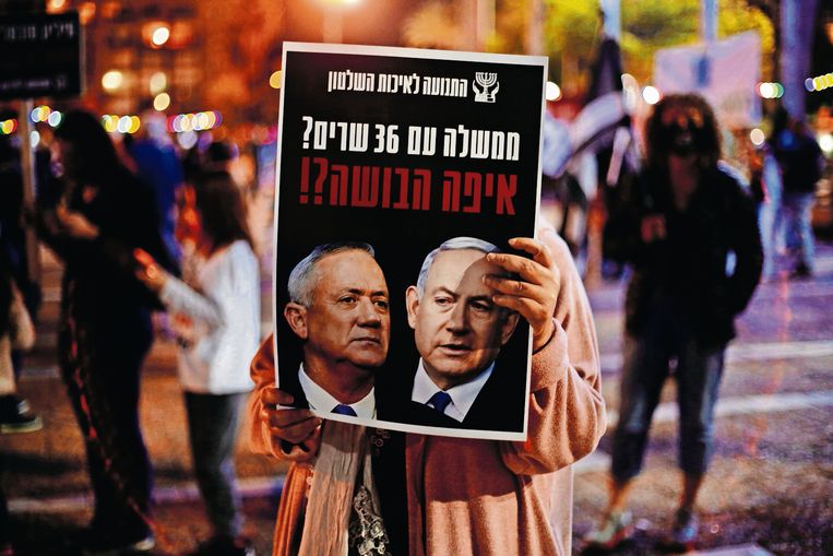 Tijdens een demonstratie in Tel Aviv tegen corruptie en de regering houdt een vrouw een bord omhoog met Gantz (links) en Netanyahu.  Beeld AP