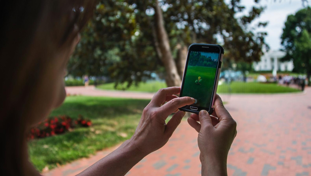 Een speler vangt een Pokémon bij het Witte Huis in Washington DC. Beeld afp