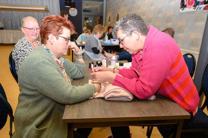 Jeanet Kollenburg (l) krijgt van vrijwilligster Tjarda Fennema nagellak op