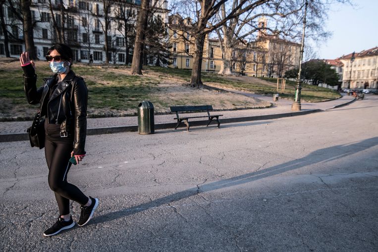 Een vrouw met een mondkapje op loopt door een verlaten Turijn . Beeld Getty Images