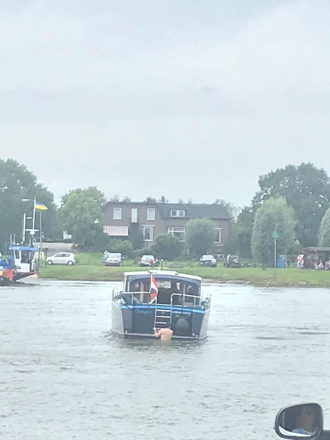 De schipper van het vastgelopen bootje probeert deze van onder los te maken. Een gevaarlijke operatie met de sterke stroming die in de IJssel staat.