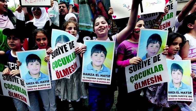 Syrische kinderen demonstreren met posters van de vermoorde 13-jarige Hamza bij het Syrische consulaat in Istanbul. Beeld 