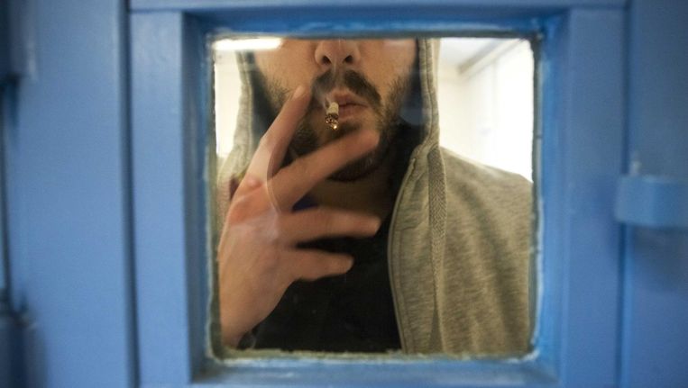 Een gedetineerde blowt achter een celdeur. Beeld anp