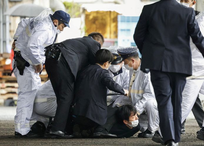 De man die zaterdag vermoedelijk een rookbom wierp naar de Japanse premier Fumio Kishida wordt meteen na zijn daad overmeesterd door politieagenten.