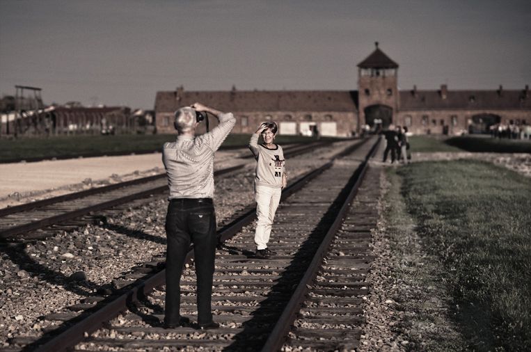 Deelnemers aan de studiereis fotograferen elkaar in het vernietigingskamp van Birkenau. Beeld Karoly Effenberger