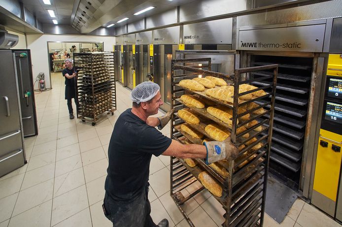 Harm Lamers (op de voorgrond) van Bakkerij Lamers in Heesch rijdt een rek met brood de oven in. De bakker maakt zich zorgen over de torenhoge energiekosten.