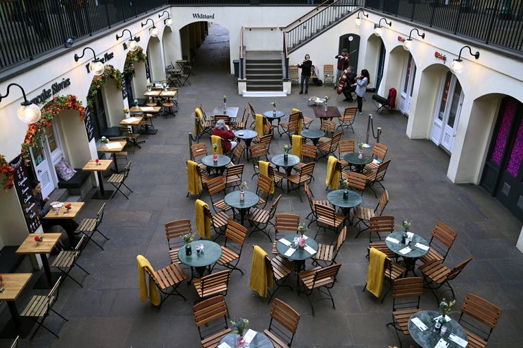 Twee mensen luisteren naar een band in een verder verlaten café in Covent Garden in Londen.  Beeld EPA